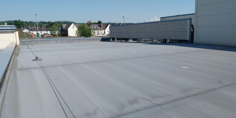 Grey single-ply membrane on a large flat commercial roof in Surrey.