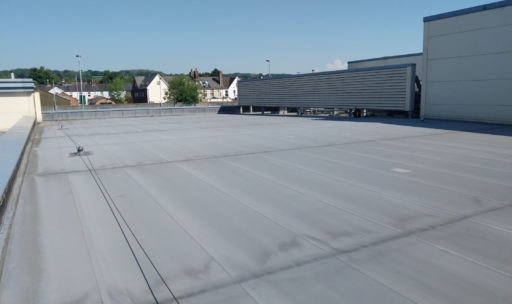 Grey single-ply membrane on a large flat commercial roof in Surrey.