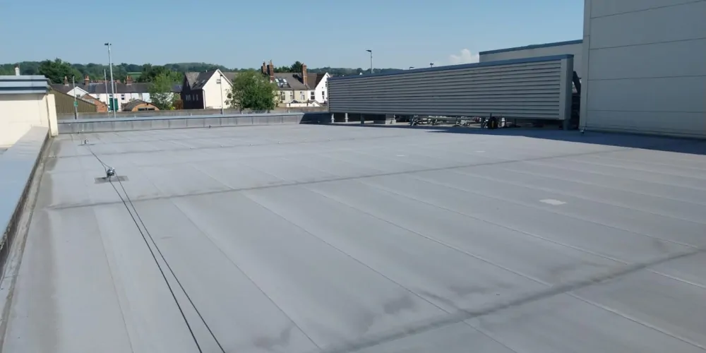 Grey single-ply membrane on a large flat commercial roof in Surrey.