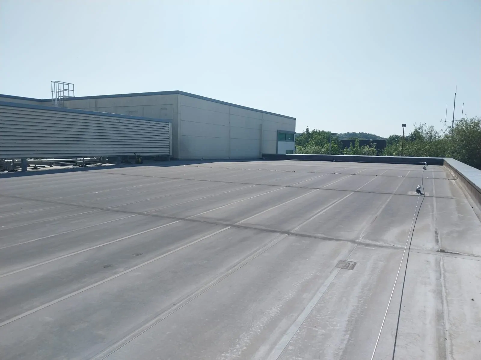 Large flat commercial roof with electronic leak detection equipment in Surrey.